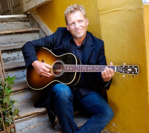 Kim Schwartz med guitar i en sommerhave